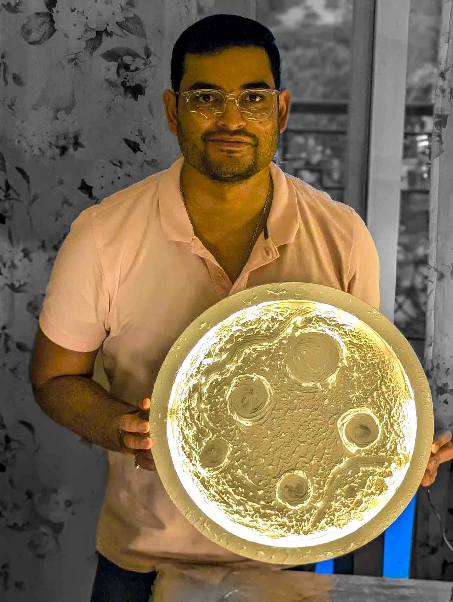 Participant holding a completed glowing moon lamp and smiling at camera.